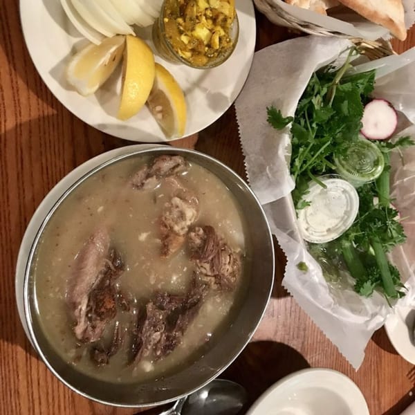 A Persian dish of meat and broth, with sides of lemon, onions, herbs, and bread.