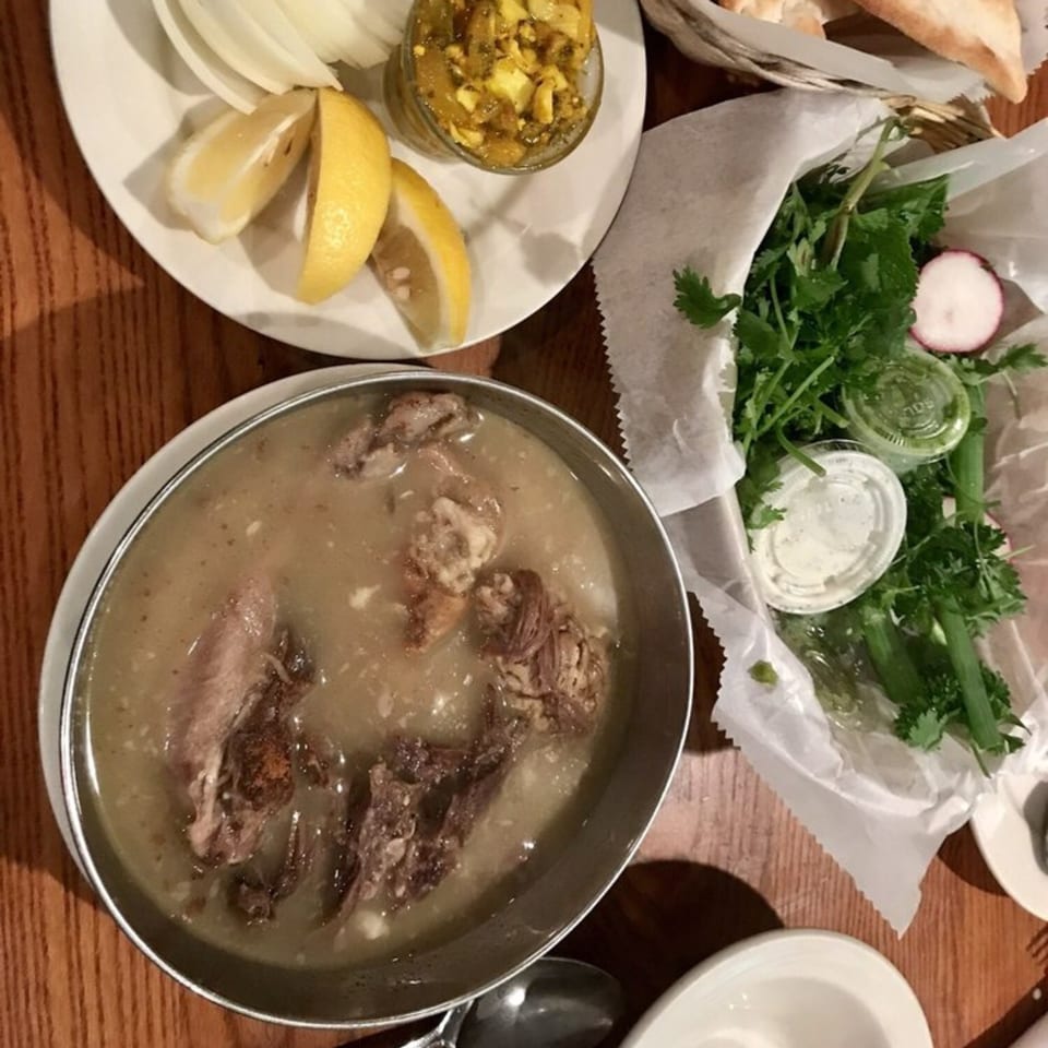 A Persian dish of meat and broth, with sides of lemon, onions, herbs, and bread.