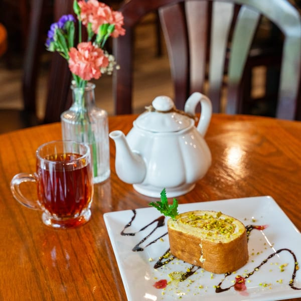 Persian roulade with pistachios, tea, and a teapot on a wooden table at Kabob Bazaar.